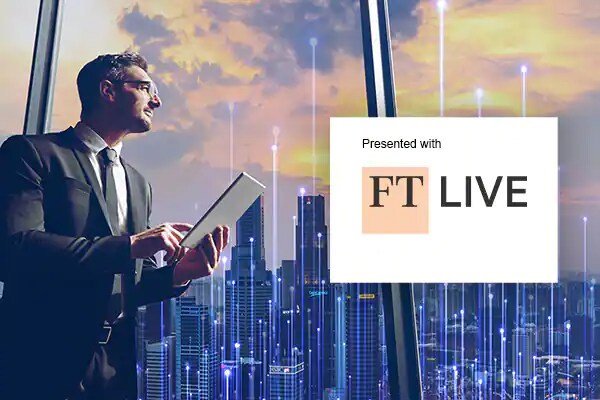 Man in formals working on a tablet and looking at a cityscape outside the window 