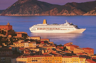 Cruise ship sailing on water between hills and a city