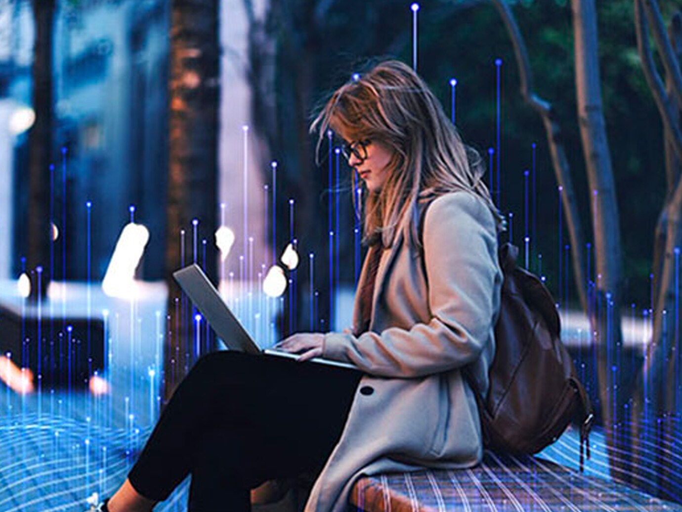 A female college student reading on a laptop while sitting on a bench