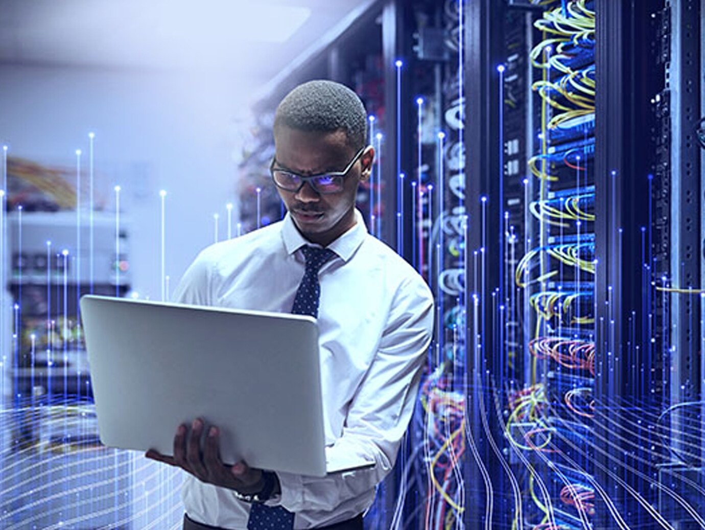A man standing and holding a laptop in a data centre