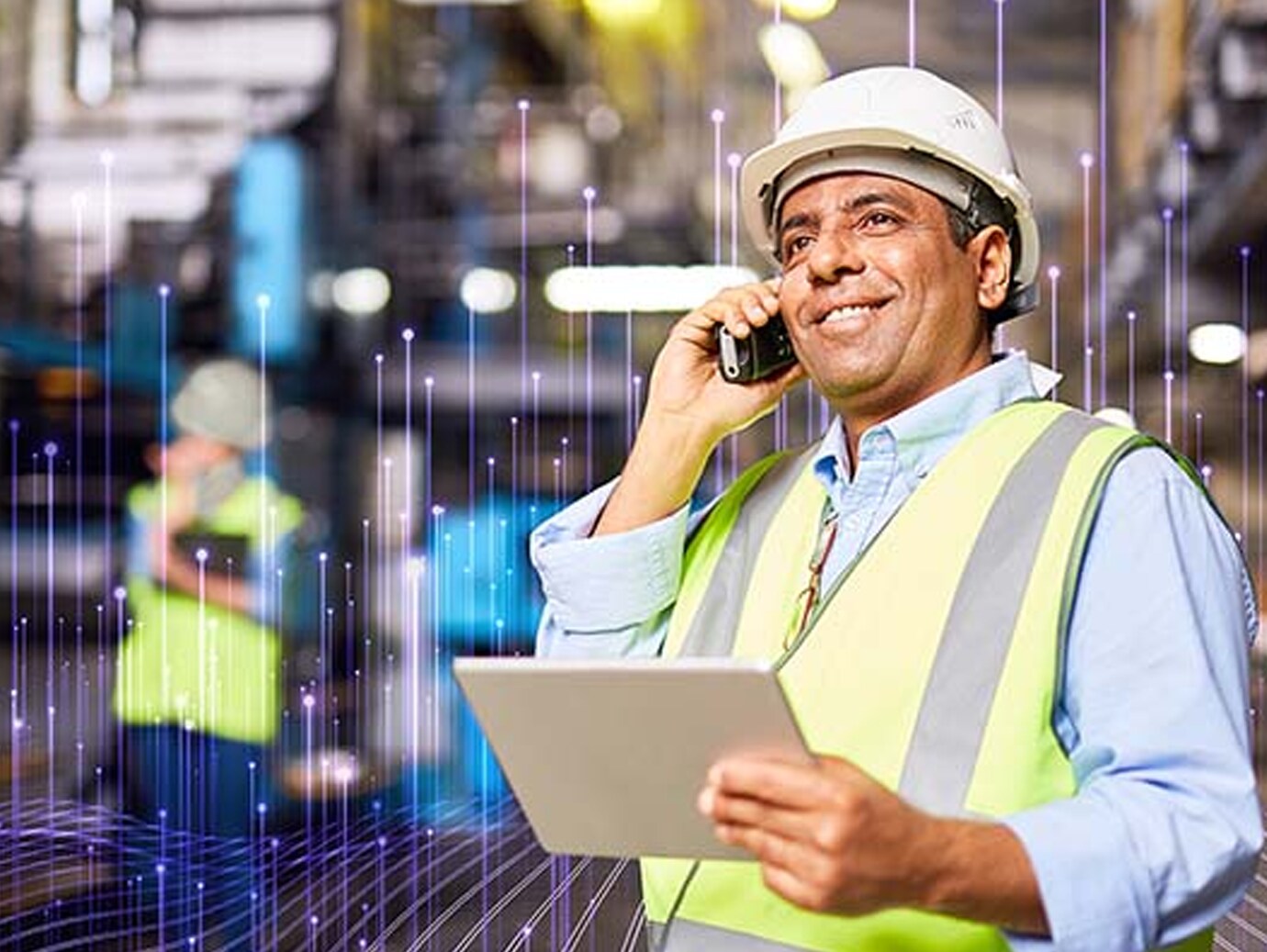 A mechanic smiling while talking over the phone in an industrial site