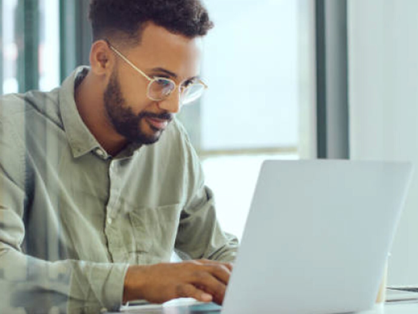 A man wearing glasses and working on a laptop