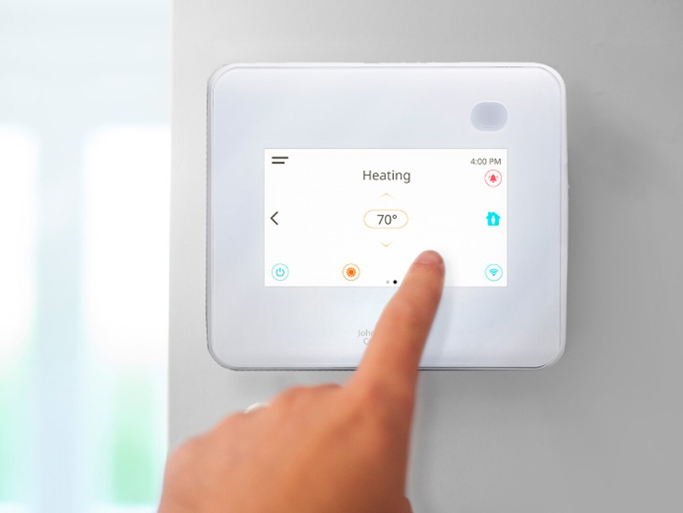 Duvardaki beyaz bir ağa bağlı termostatı çalıştıran bir kişinin yakın çekimi