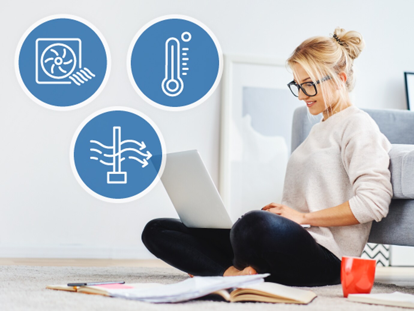 Kanepenin yanında oturan ve dizüstü bilgisayarda çalışan bir kadın, üstünde ağ bağlantılı termostatların özelliklerini gösteren simgeler var