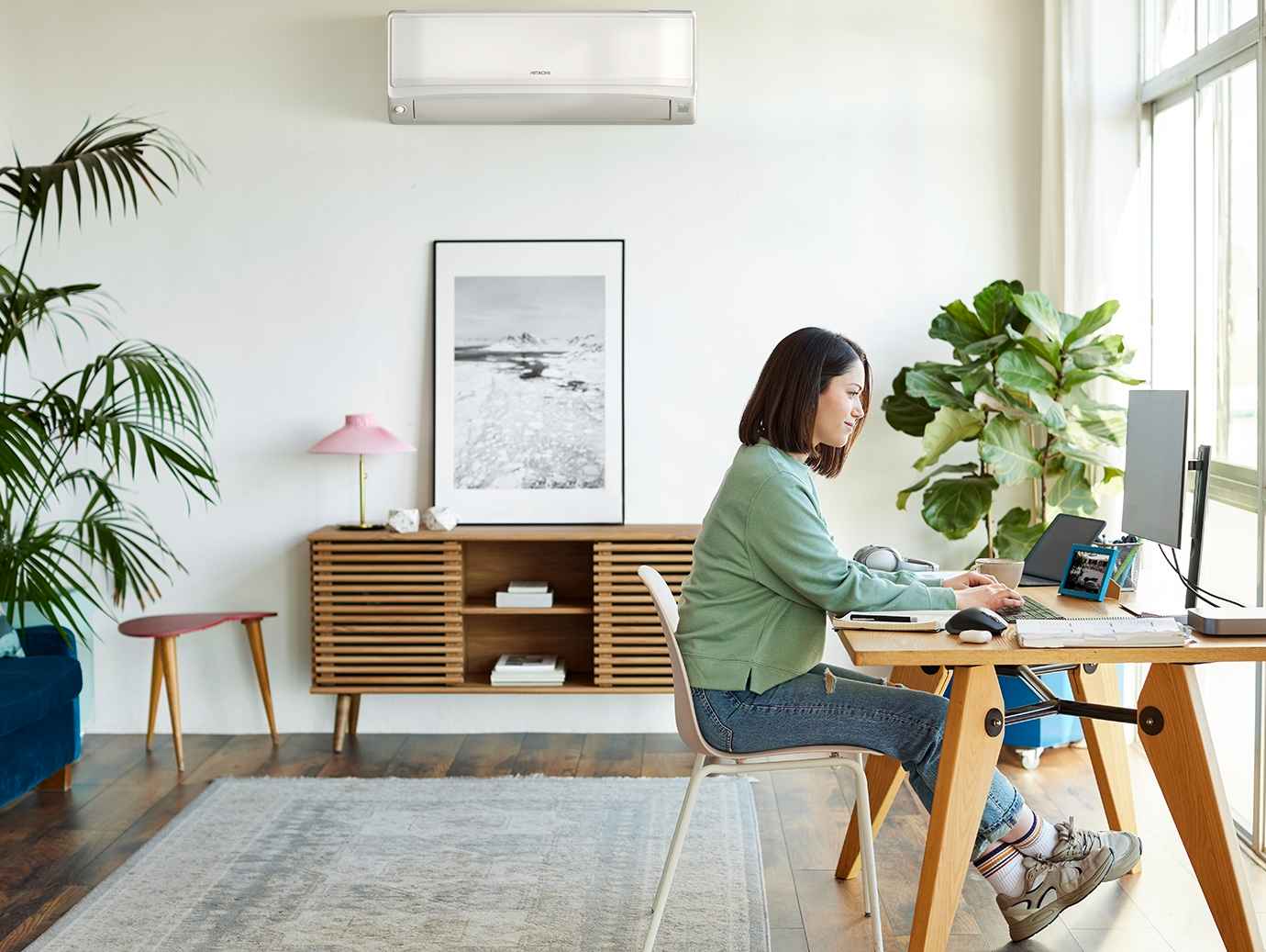 Woman working on her desktop in her room with indoor plants 