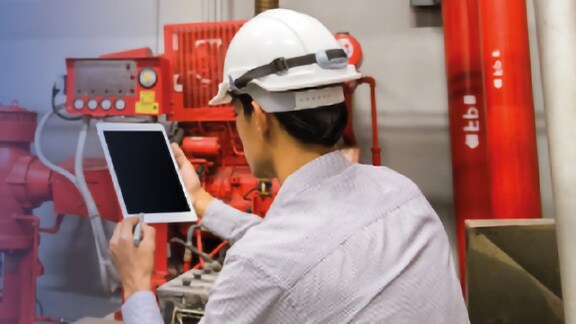 Man wearing a safety helmet using a tablet
