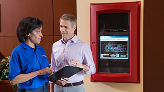 two people in conversation standing in front of a control panel