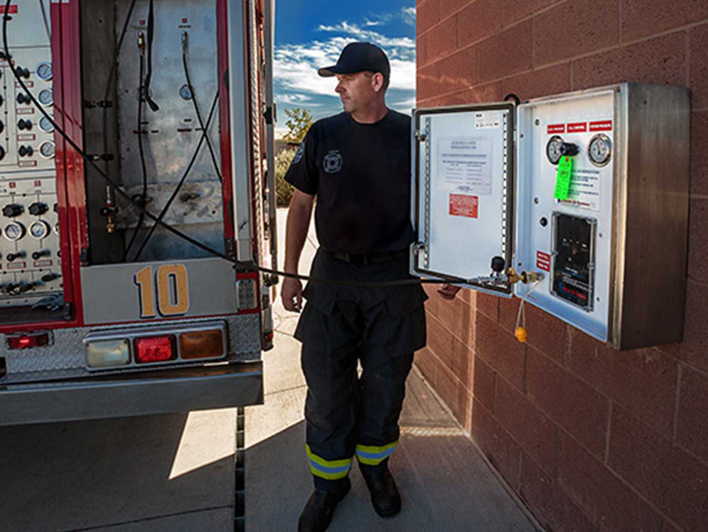 A firefighter using a FARS standpipe to refill tank