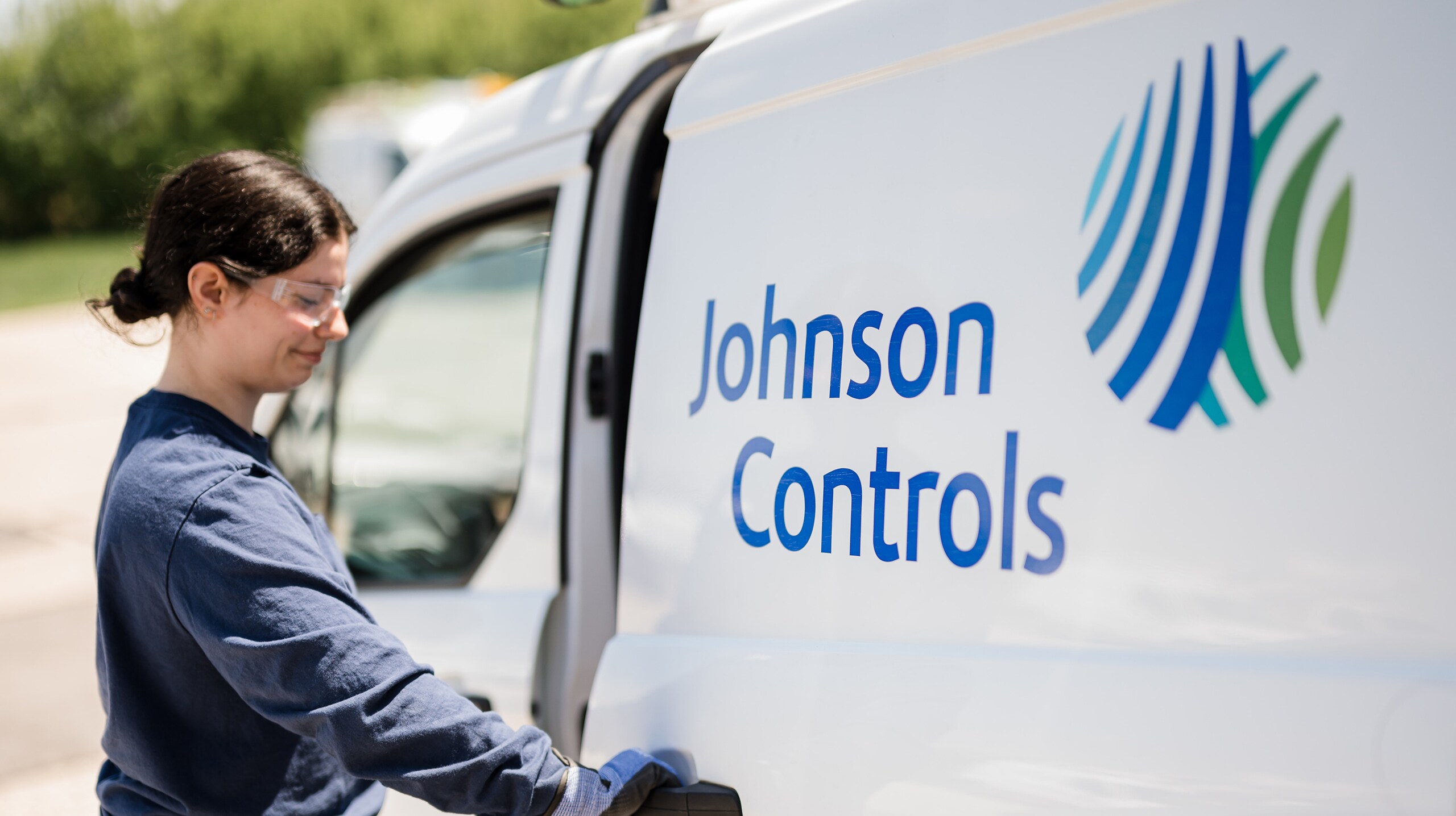 Johnson Controls expert building technician working alongside a company vehicle featuring the Johnson Controls logo.