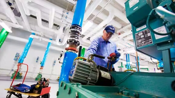 A man working on a chiller unit in a facility