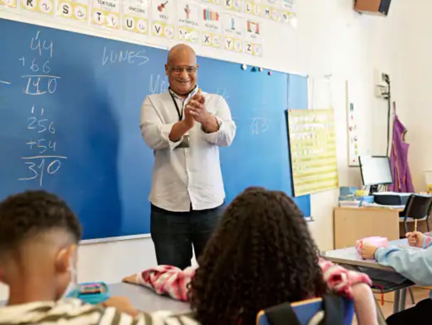 A teacher clapping in a classroom