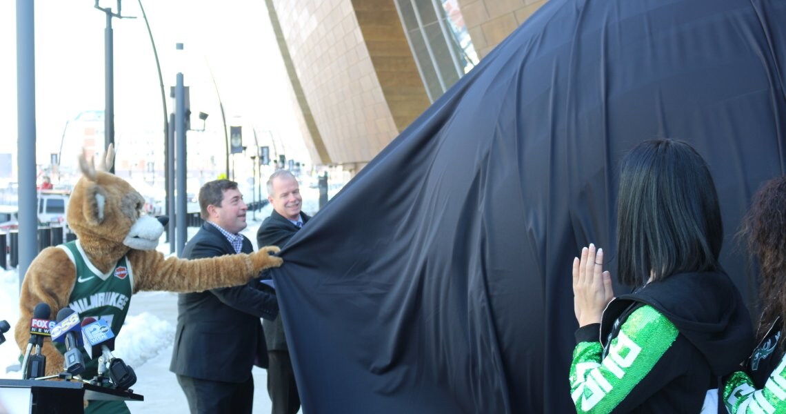 Peter Feigin, George Oliver, Grady Crosby and a Milwaukee Bucks mascot unveiling the Johnson Controls sculpture at Fiserv Forum