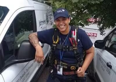 Iesha Whylie, electronic systems technician installer at Johnson Controls, posing by a van