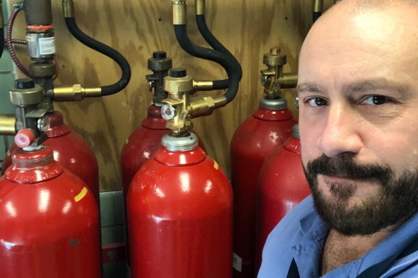Mike Siragusa, a fire technician at Johnson Controls, standing near a set of fire extinguishers 