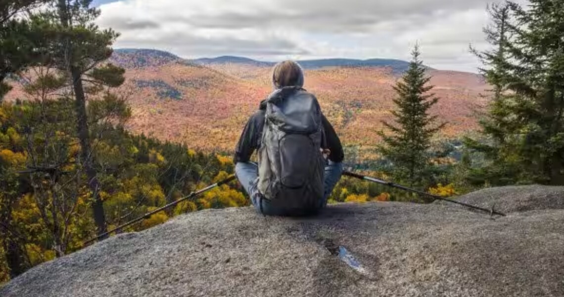 Rear view of a trekker sitting and gazing at the mountains