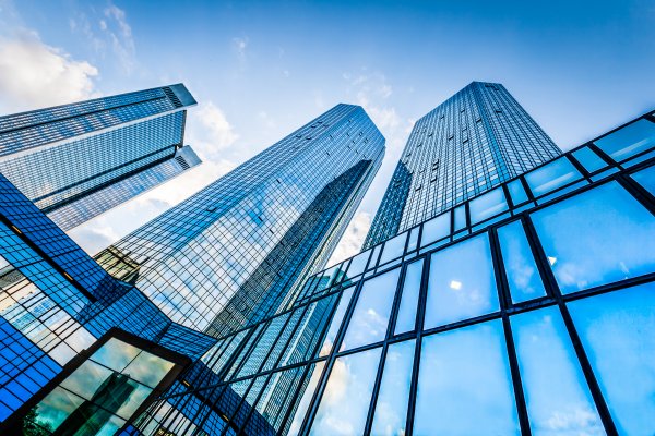 Frog's-eye view of blue multi-storey buildings against a clear sky 