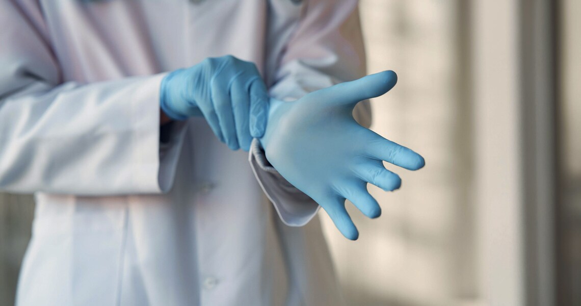 Close-up of a doctor putting on rubber gloves