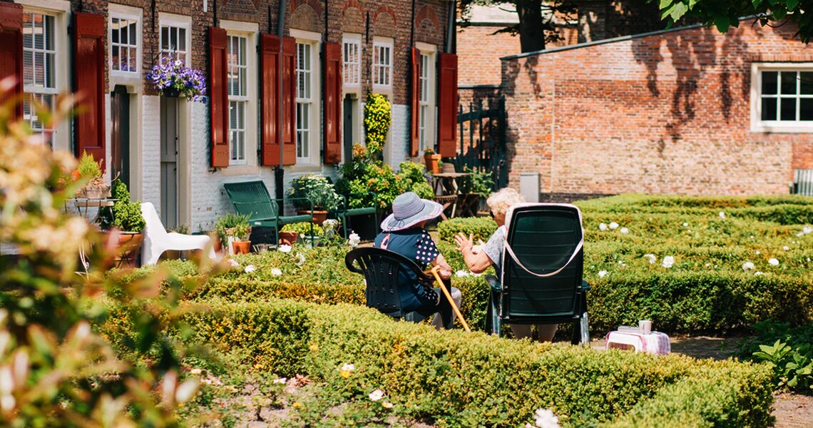 Rear view of two elderly women sitting at a porch and talking