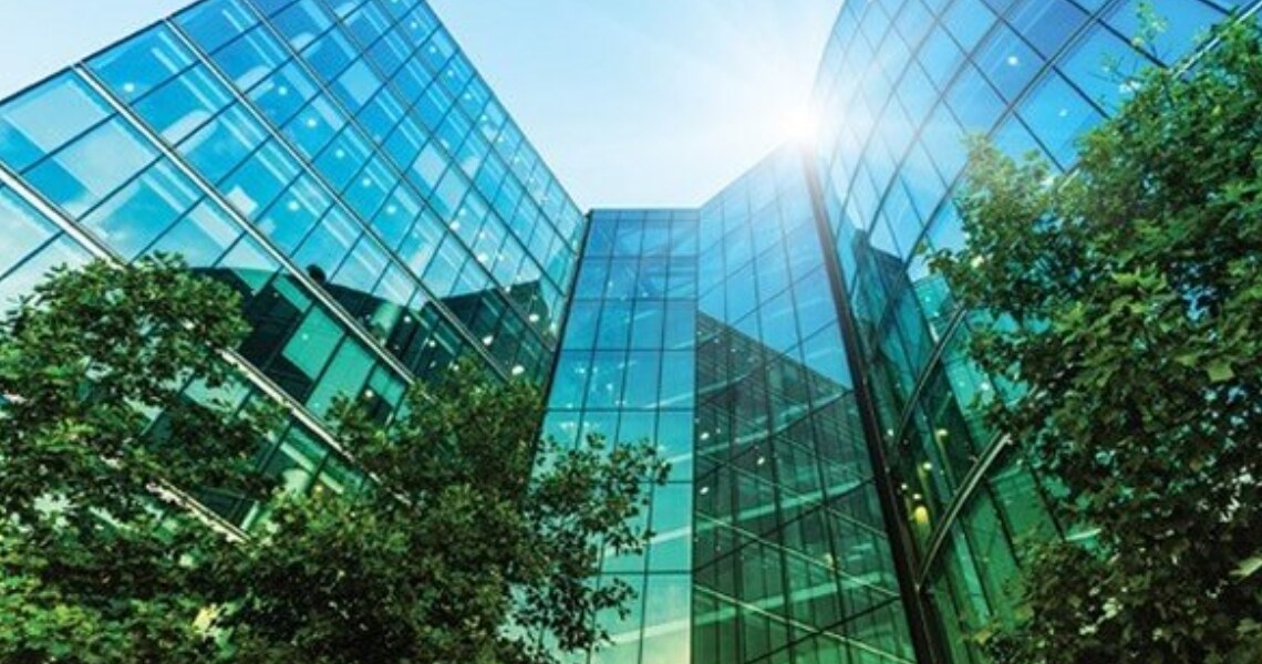 Frog's-eye view of glass buildings surrounded by trees