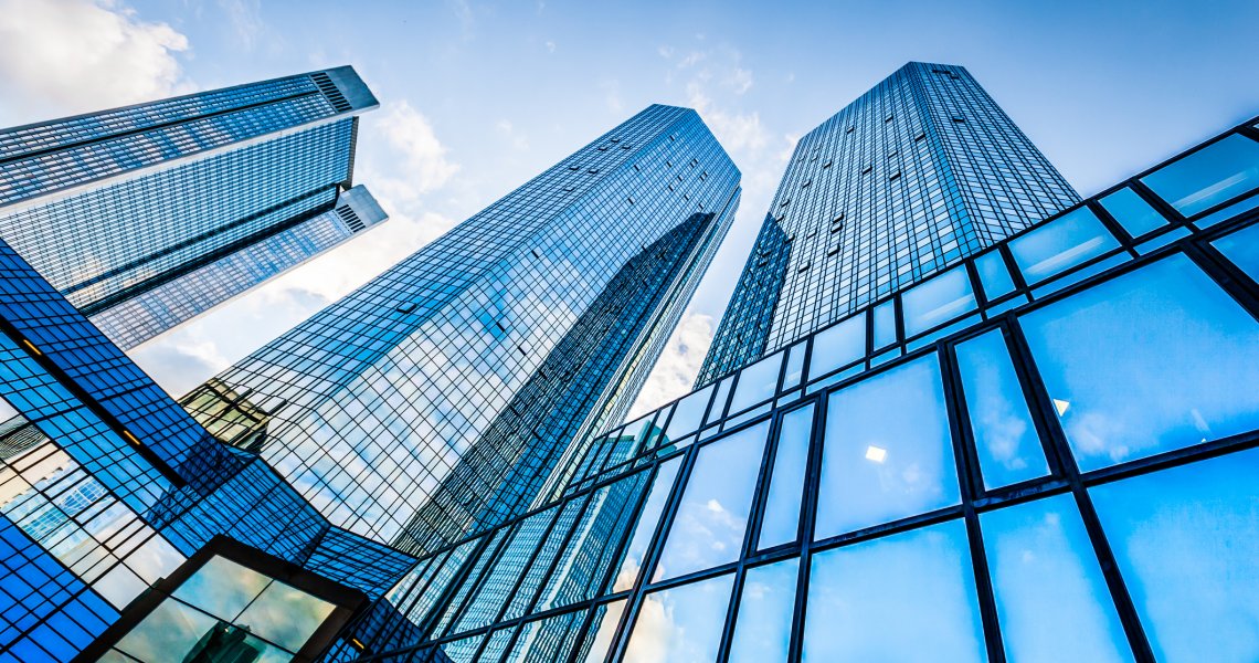Frog's-eye view of blue multi-storey buildings against a clear sky