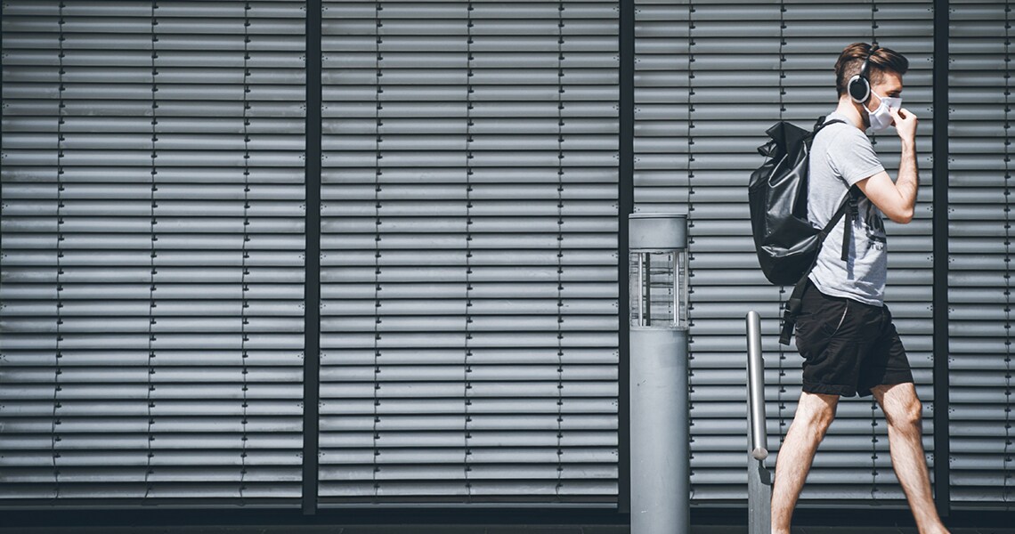 Man wearing a backpack and walking, while listening to music on his headphones