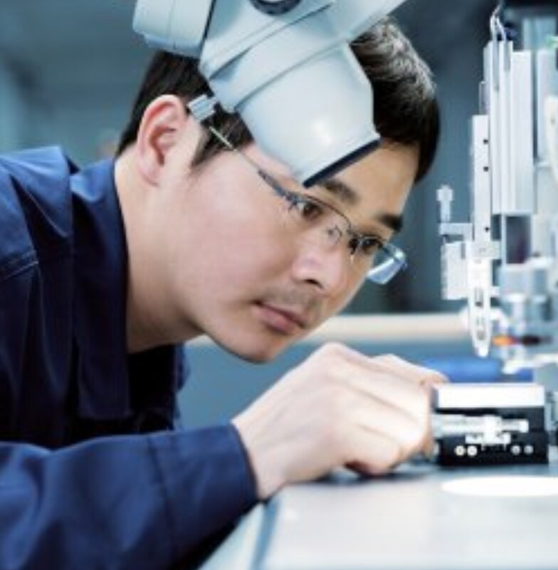 A male researcher examining a slide under an electron microscope