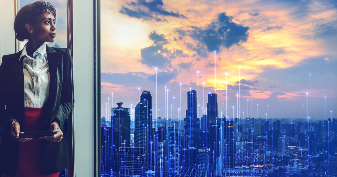 Businesswoman holding a tablet and gazing at a cityscape overlaid with OpenBlue graphics