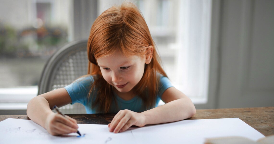 A young sitting at a table and drawing
