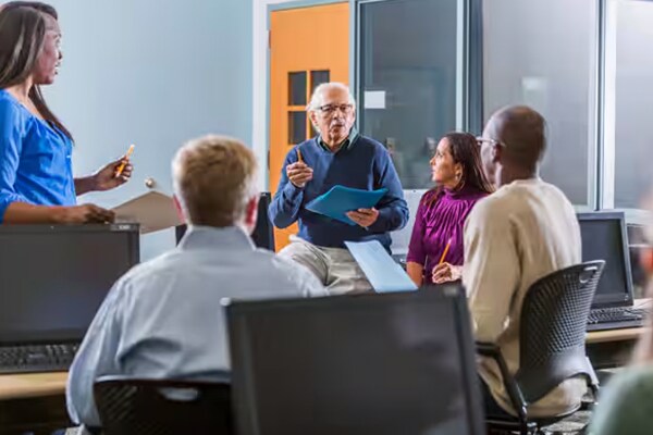 A group of people seated around a professor giving a lecture