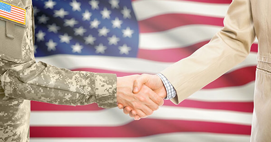 Two people shaking hands, with the American flag in the background