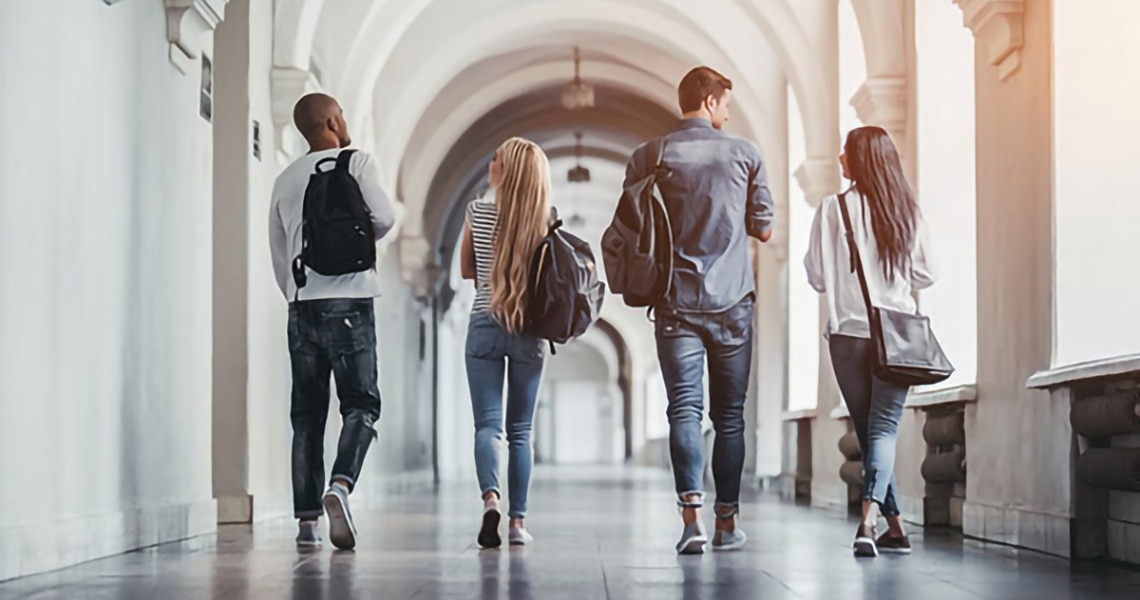Rearview shot of group of students walking in university corridor