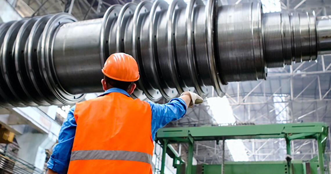 Industrial engineer wearing high visibility jacket and safety helmet inspecting a steel machine