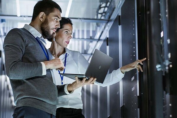 Man and woman inspecting a data centre, with the man holding a laptop