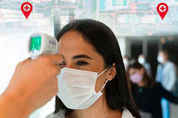 Security personnel checking temperature of a woman at a health checkpoint