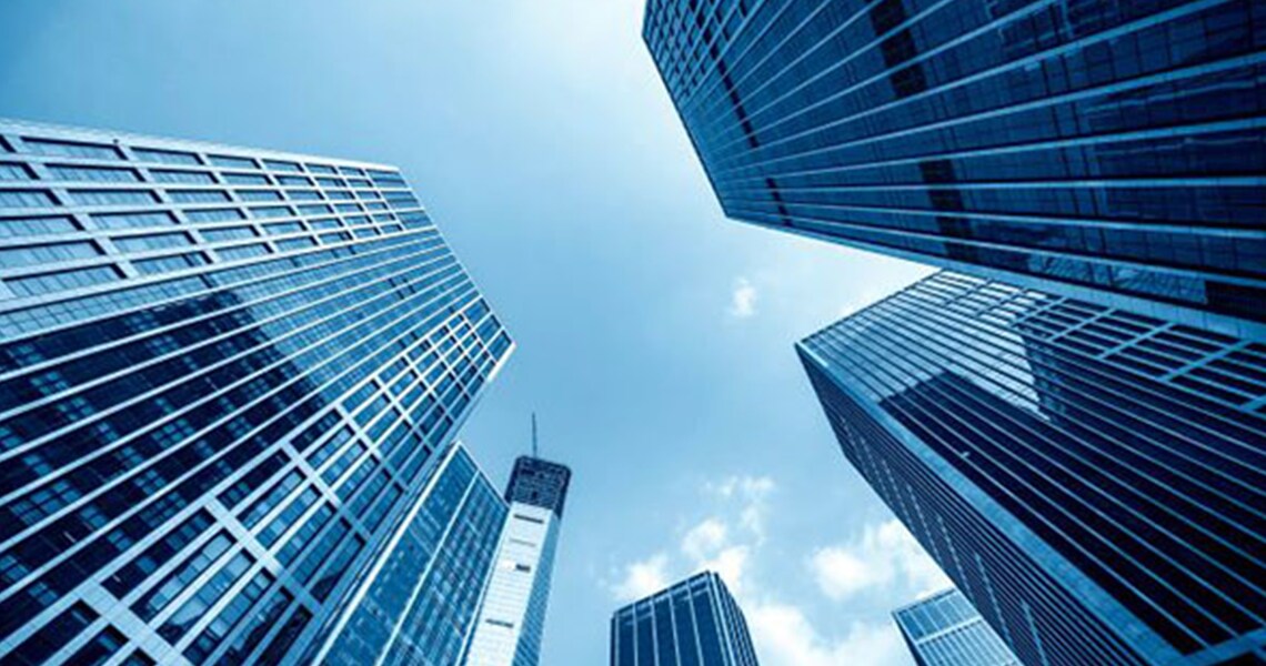 Frog's-eye view of blue multi-storey buildings against a clear sky