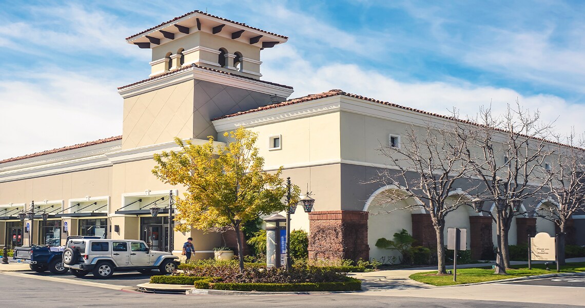 A commercial building surrounded by trees and parked vehicles