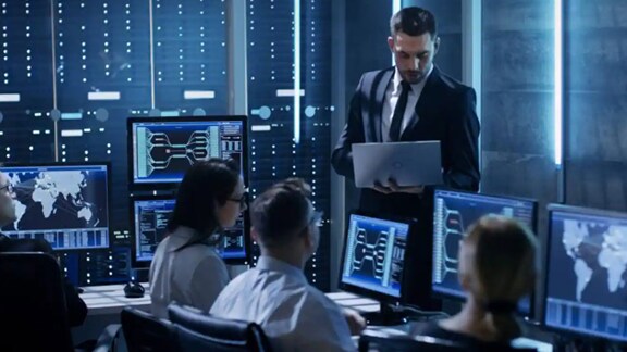 Employees working on their desktops in a control room