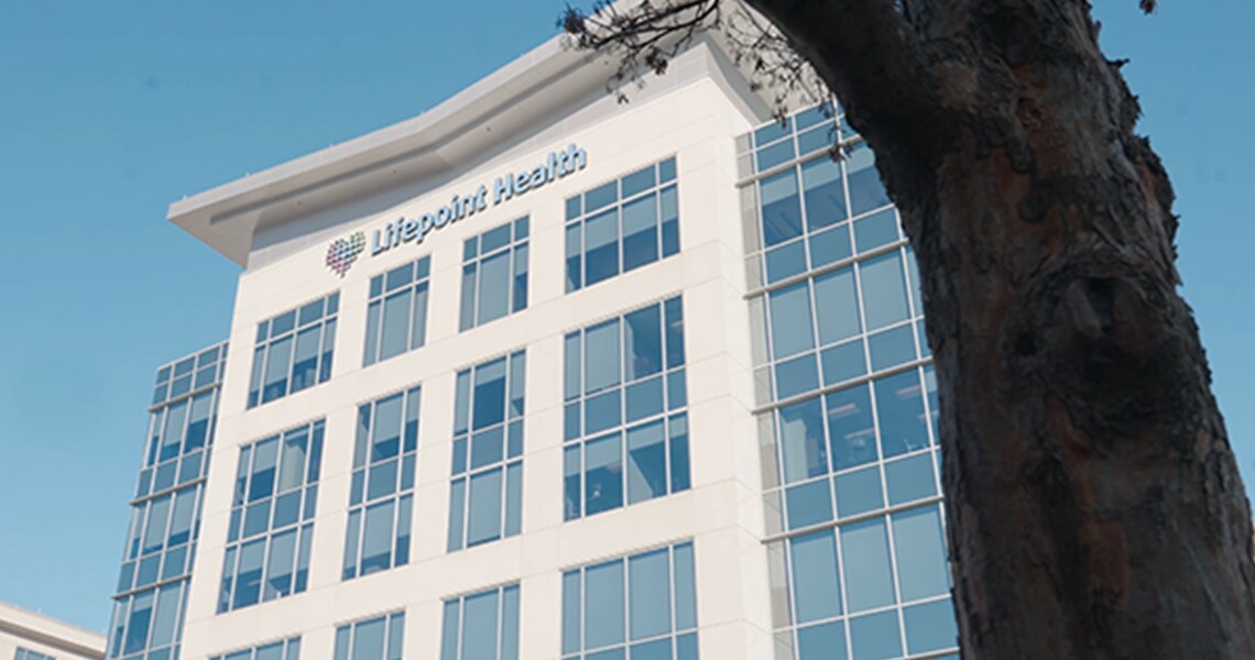 Frog's-eye view of a hospital building behind a tree