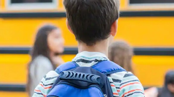 Rear view of a kid carrying a backpack in school premises