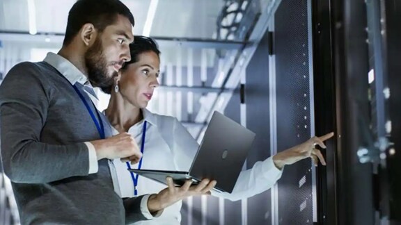 Man and woman using a laptop in a data center