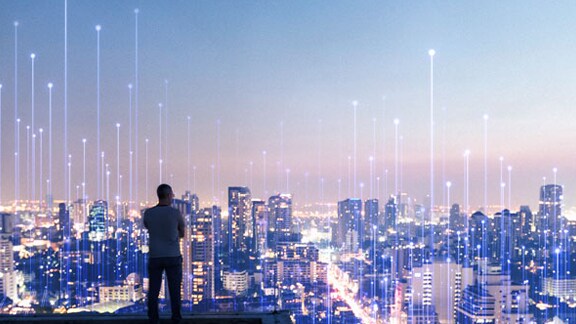 Man looking at the city from a rooftop, overlaid with a graphic of transmission nodes