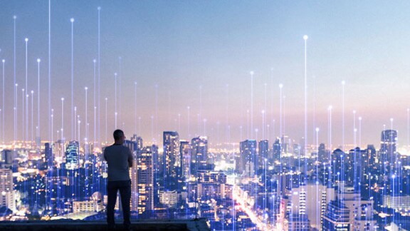 Man on top of a high-rise building staring at the skyline with an overlay of Openblue graphics