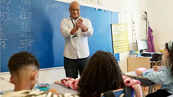 Teacher clapping his hands while teaching a group of students in a classroom