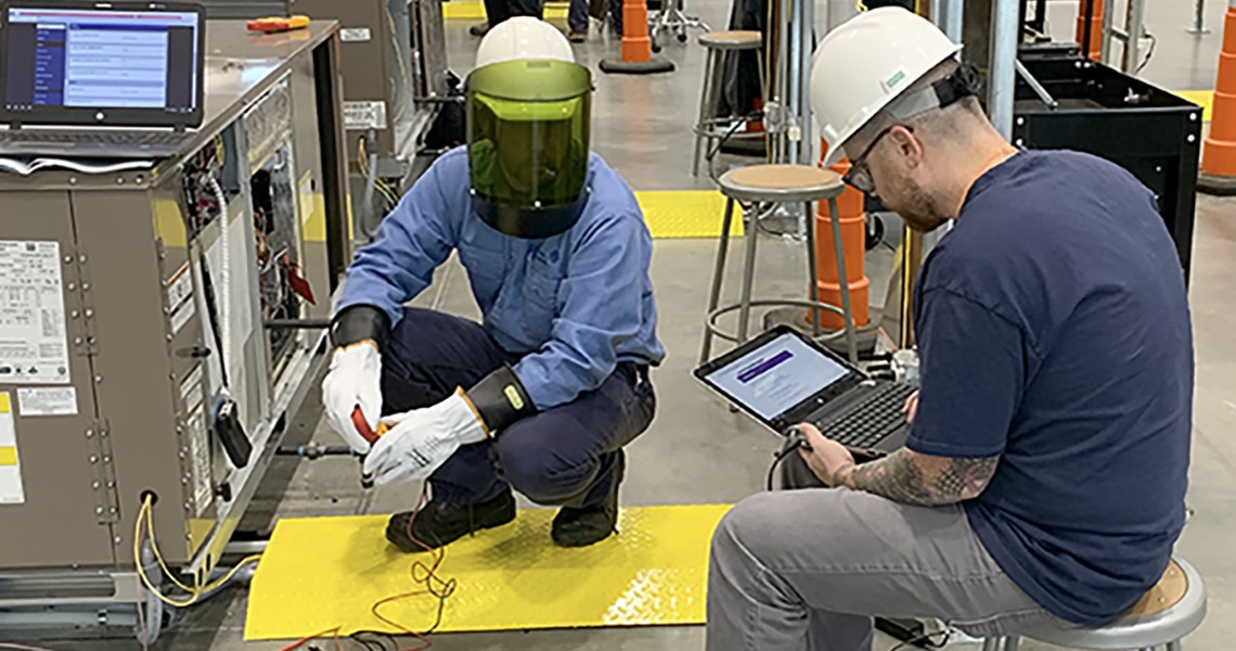 Two engineers in safety helmets, working on an HVAC equipment