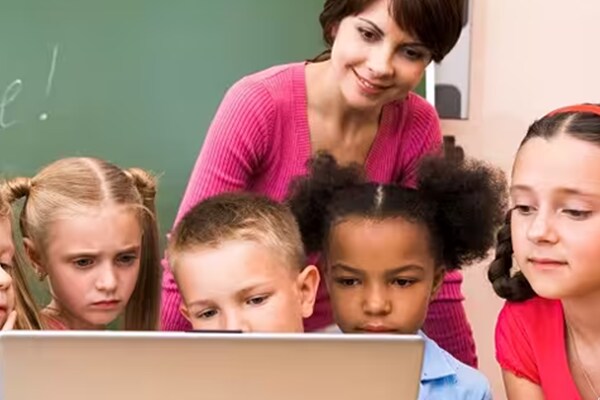 Teacher using a laptop to teach kids in a classroom