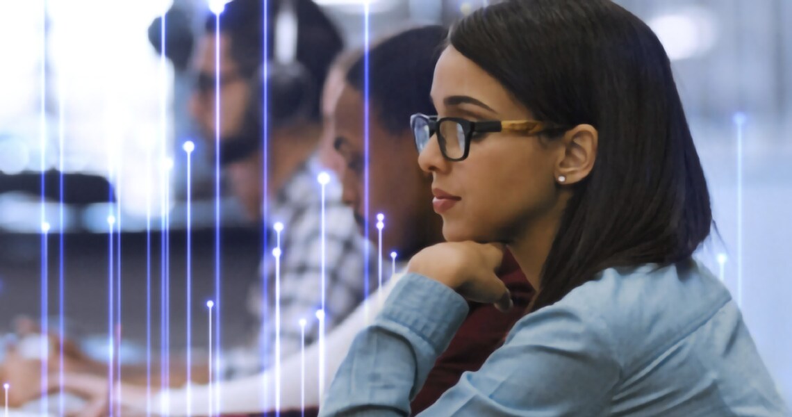 A young female student working on a desktop, seated beside a row of fellow students