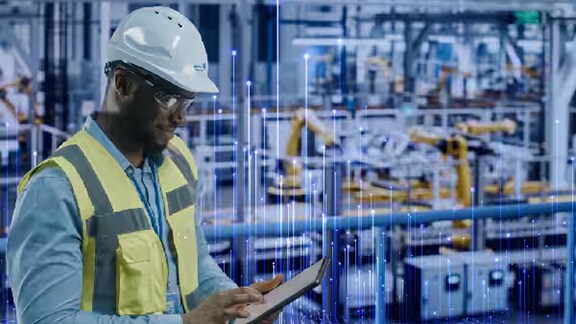 An engineer scrolling on a tablet in an industrial facility