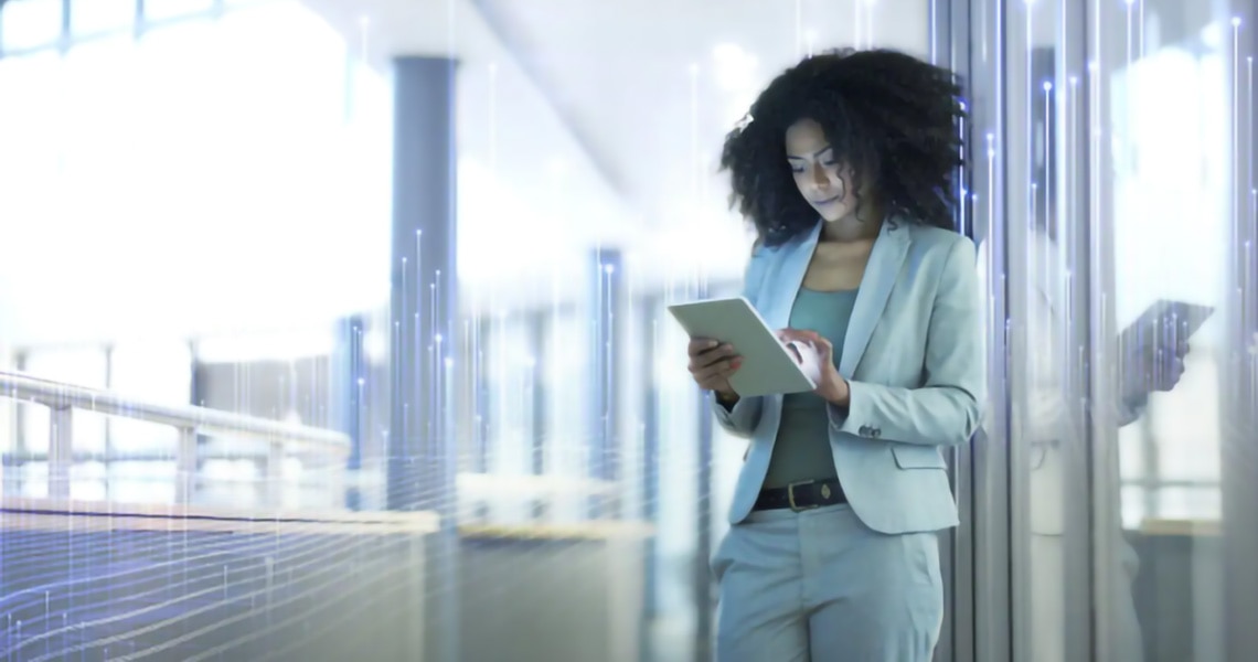 A businesswoman scrolling on a tablet in an office passageway