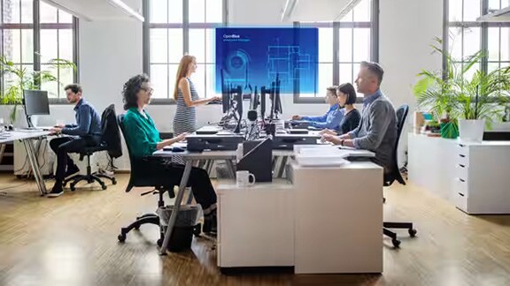 A group of colleagues seated at desktops in an office