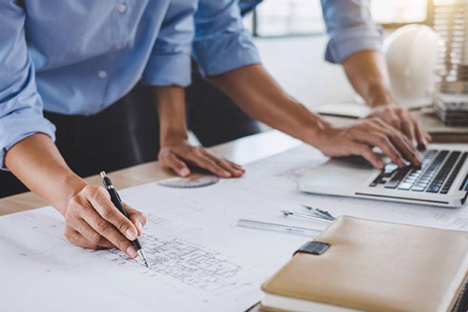 Close-up of a pair of engineers measuring blueprints